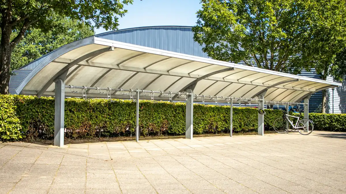 Long carport à toit cintré sur poteaux fins, avec place pour plusieurs voitures