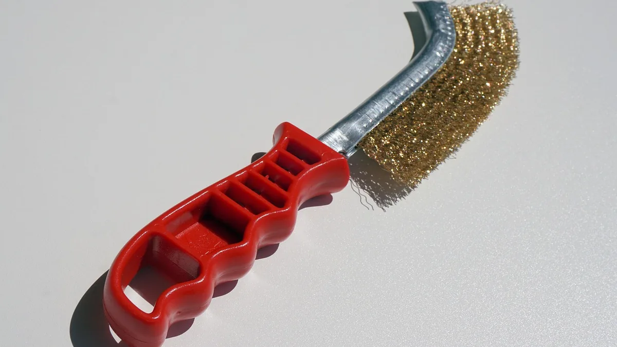Brosse métallique à manche rouge, l'outil de base pour brosser la rouille