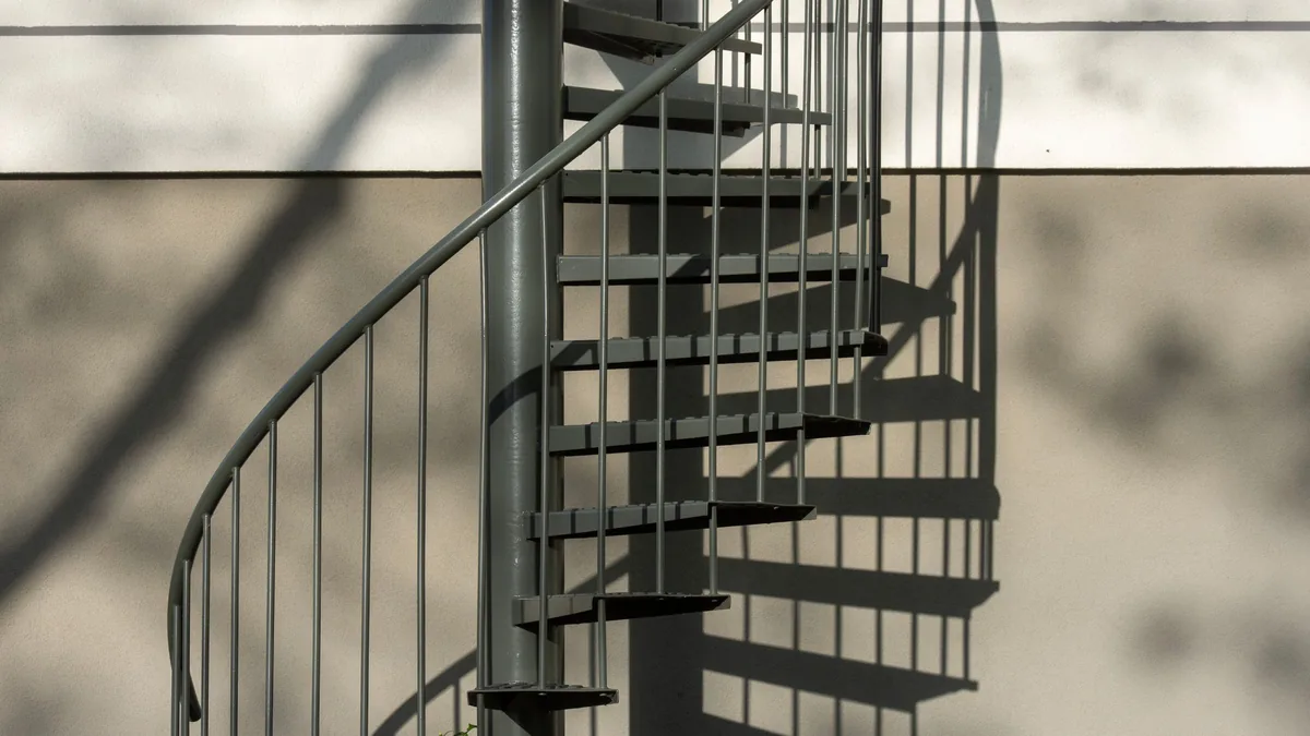 Escalier colimaçon métallique à marches ajourées et rampe à barreaux fins