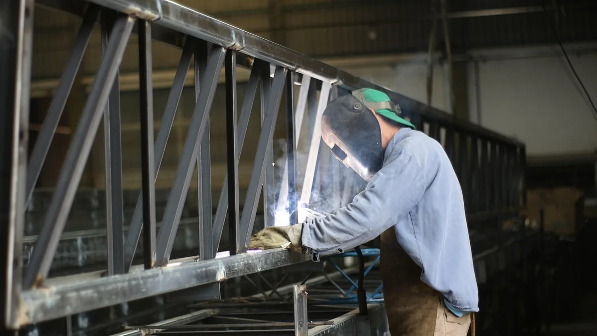 Métallier qui soude une structure en acier dans un atelier