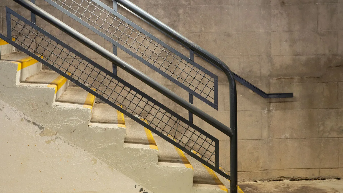 Garde-corps à remplissage en grillage et main courante, sur un escalier en béton