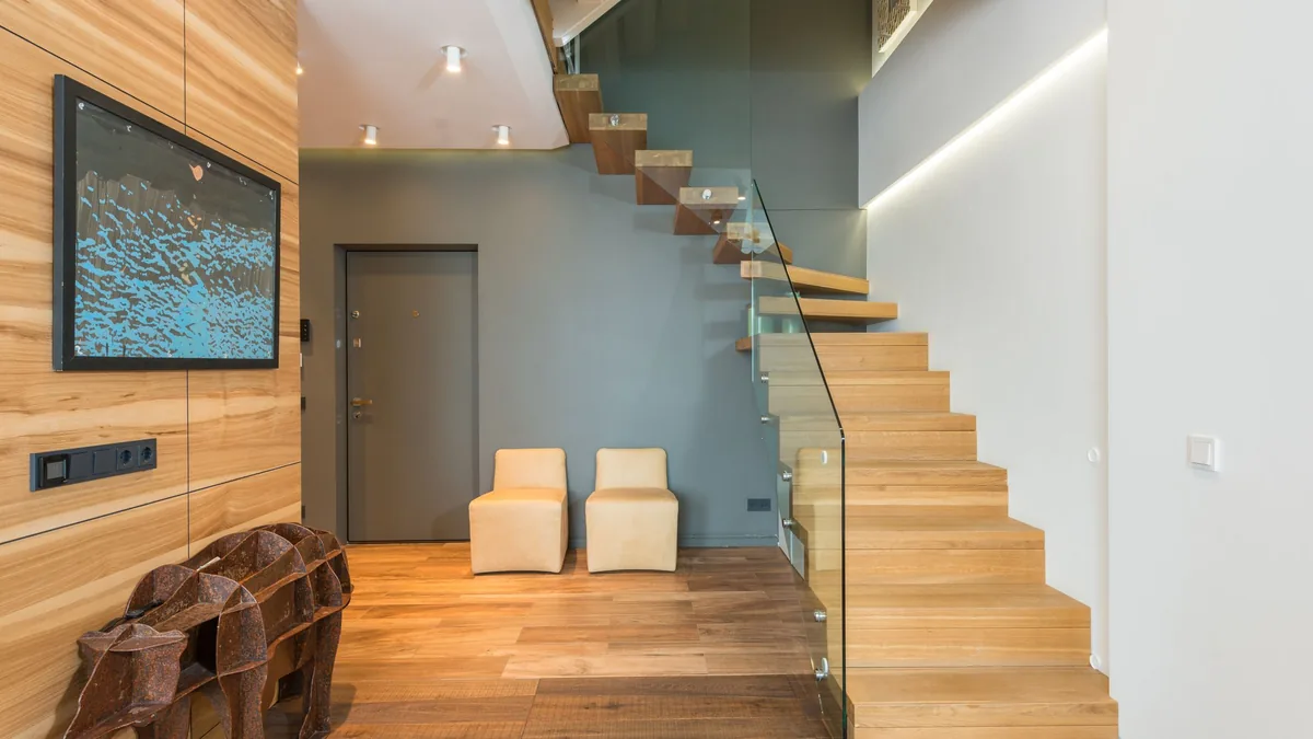 Garde-corps en verre sans cadre apparent le long d'un escalier en bois