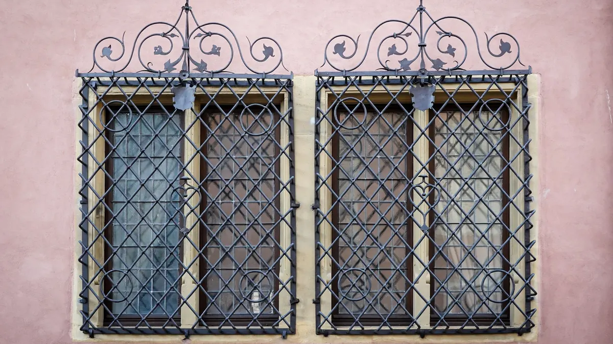 Deux fenêtres protégées par des grilles de fer forgé ouvragées