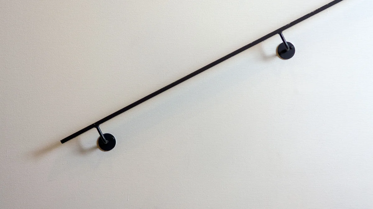 Main courante noire fixée au mur par deux supports scellés
