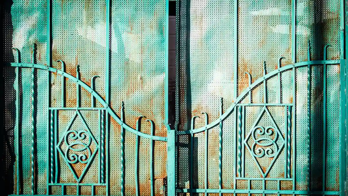 Portail en fer forgé turquoise à motifs de losanges et volutes