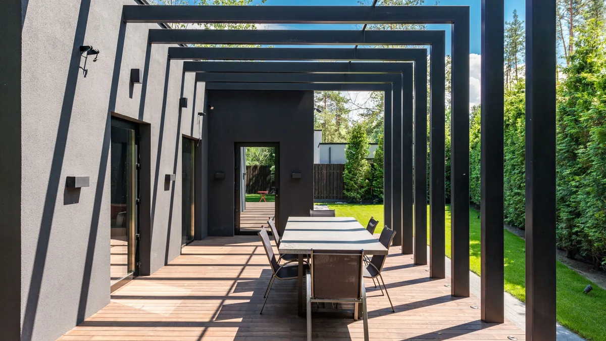 Pergola à structure métallique noire sur une terrasse en bois