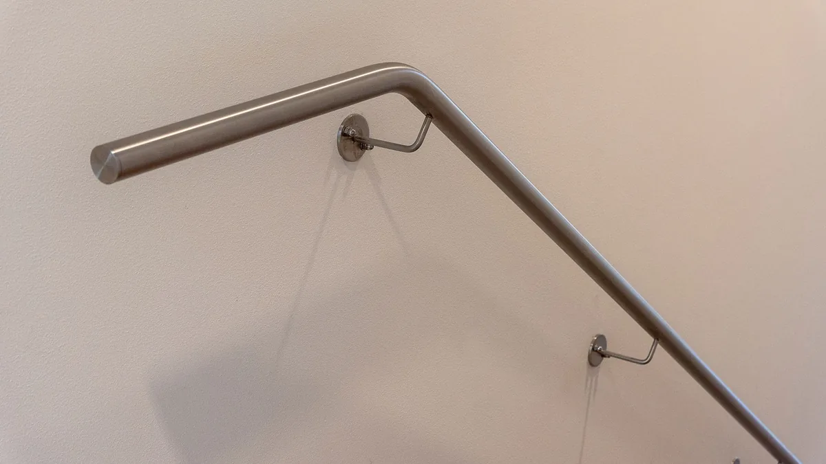 Main courante tubulaire en inox, coudée et fixée au mur