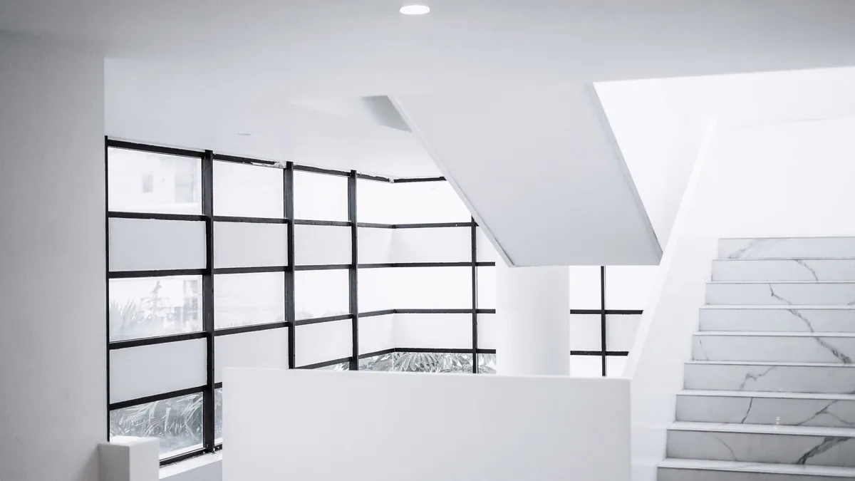 Baie quadrillée à cadre d'acier noir au-dessus d'un escalier blanc